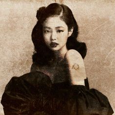 an old photo of a woman with her hand on her shoulder, wearing a black dress