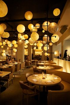 an empty restaurant with many tables and lamps hanging from the ceiling over it's dining area