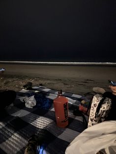 two people are sitting on the beach at night with their cell phones in their hands