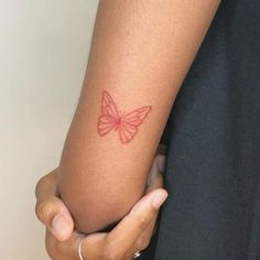 a woman's arm with a red butterfly tattoo on the left side of her arm