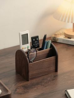 a wooden desk with a phone, pen holder and glasses on the table next to it