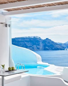 an outdoor bathtub overlooking the ocean with mountains in the backgroung and blue water