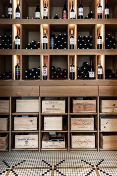 wine bottles are lined up on shelves in a room with black and white tile flooring