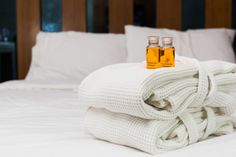 two bottles of essential oils sit on top of folded towels in front of a bed