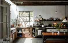 a kitchen filled with lots of counter space and wooden furniture next to an open window