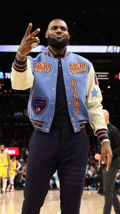 a man standing on top of a basketball court with his hand up in the air