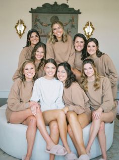 a group of women sitting next to each other on top of a white round bed