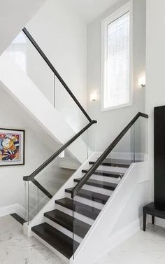 a white and black stair case in a house with marble flooring on the ground