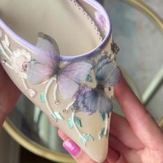 a hand holding a pair of shoes with butterflies on them