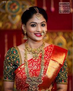 a woman in a red and gold sari with jewelry on her neck, posing for the