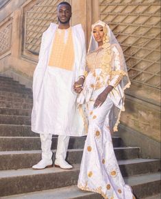 a man and woman dressed in white standing on steps