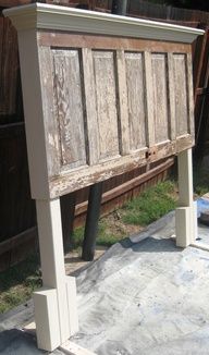 an old wooden bed frame sitting on top of a cement slab next to a fence