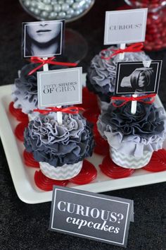 two cupcakes with red and white decorations on them, one has a sign that reads how to host a fifty shades of grey ladies'night party + free printables