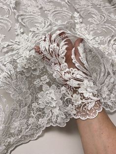 a woman's hand is touching the sheer lace on her wedding dress that she has made