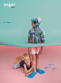 two children in swimsuits and goggles standing next to each other on the ground