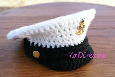 a small black and white hat on top of a wooden table with a gold button