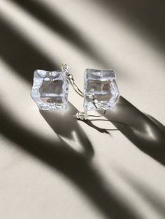 the shadow of a pair of earrings is cast on a white surface with light coming through it