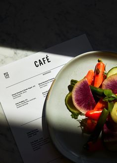 a white plate topped with veggies next to a piece of paper on top of a table