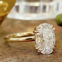 a close up of a ring on a table with an apple and glass in the background