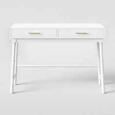 a white desk with two drawers and gold handles