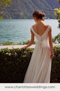 a woman in a wedding dress looking at the water