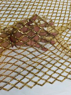 someone is holding onto some gold colored mesh with their hand on top of the net