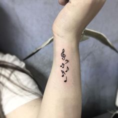 a woman's wrist tattoo with musical notes on the left side of her arm