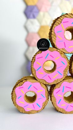 four donuts with pink frosting and sprinkles stacked on top of each other