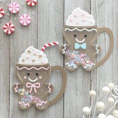 two decorated gingerbread cookies sitting next to each other on top of a wooden table