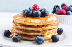 a stack of pancakes topped with blueberries and raspberries