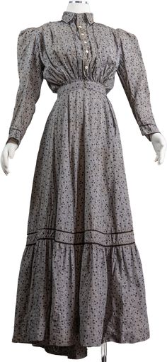 This is a gorgeous 1890s cotton calico wrap dress. The dress is printed with adorable black shamrocks and white dots and is on a gray checked base. The dress has a high collared neckline and buttons down the front with a puffy almost pigeon-breasted style top. It has large puffy leg of mutton sleeves that are looser for the more casual wear of this dress. The dress is fitted at the waist with a waistband that has two hooks and eyes that keep the dress closed. The skirt wraps to the left to fasten with a hook to the waistband and then there is a slit in the skirt that can be used to access a tie-on pocket if you would like. The slit is well hidden and does not open. The skirt of the dress is a wonderful full A-line with a flounce at the hem. At the center back of the skirt the dress has box 1880s Dresses Casual, Early Victorian Dress, 1890s Dress Poor, Late Victorian Dress, Victorian Wrapper Dress, Victorian Summer Dress, 1880s Day Dress, Plus Size Victorian, Wrapper Dress