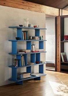 a blue shelf with books on it in a living room next to a wooden floor