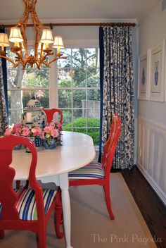 a dining room table with red chairs and a white table in front of a window