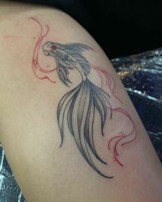 a woman's arm with a tattoo on it that looks like a goldfish