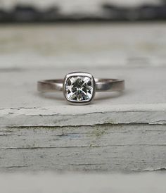 a close up of a ring with a diamond in it on a piece of wood