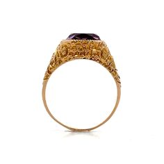 This Victorian-era cocktail ring features a striking 4.18-carat cushion cut amethyst securely set in a bezel setting. The rich, royal purple of the amethyst is beautifully complemented by the polished 14 karat yellow gold, creating a harmonious blend of color and craftsmanship. The decorative carved mounting adds sophistication and charm, showcasing intricate details that reflect the workmanship of the era. Perfect for both elegant evenings or vintage flair for everyday style, this ring is a timeless piece that will continue to be cherished. Luxury Victorian Amethyst Ring In Purple, Victorian Gold Amethyst Ring In 14k Gold, Luxury Yellow Gold Victorian Amethyst Ring, High-end Vintage Amethyst Ring For Formal Occasions, Engagement Ring Style Guide, Victorian 14k Gold Amethyst Ring Collectible, Ring Style Guide, Amethyst Cocktail Ring, Platinum Rose Gold