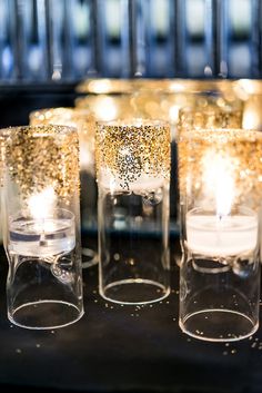 candles are lit in glass vases with glitter on them