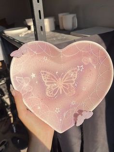 a person holding up a pink heart shaped box with a butterfly on the front and side