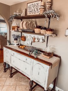 an old buffet table with plates and bowls on it in a room that has tile flooring