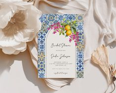 a wedding card with lemons and flowers on it next to some white fabric material