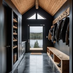 the inside of a house with black walls and wood ceilinging, open doors leading to a lake