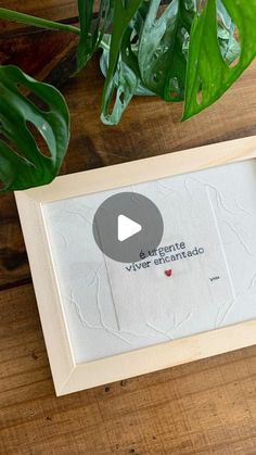 a wooden table with a plant on top of it and a framed photo in front of it