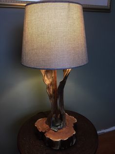 a lamp that is sitting on top of a wooden table next to a framed picture