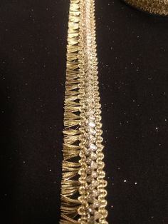 a close up view of the side of a gold sequinned ribbon on a black background