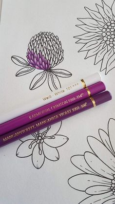 two purple pens sitting on top of a piece of paper next to some white flowers