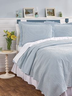 a bed with blue and white bedspread, pillows and pictures on the wall