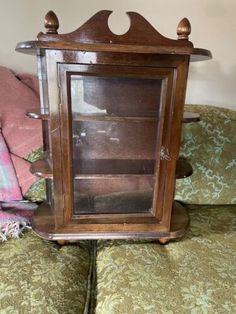 an old wooden clock sitting on top of a green couch