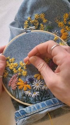 someone is stitching flowers on a jean jacket