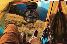 a person laying in a tent with their feet on the ground next to a fan