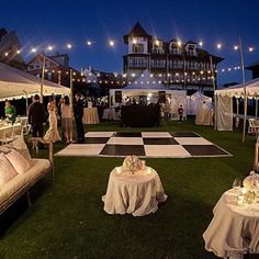 an outdoor event with tables and couches set up on the lawn at night time